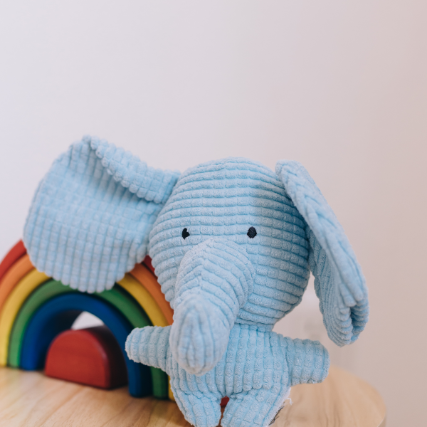 A blue plush elephant next to stack of rainbow blocks