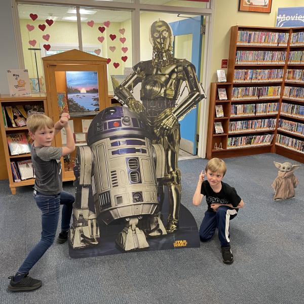 C3PO and R2D2 cardboard cutouts with two young patrons posing